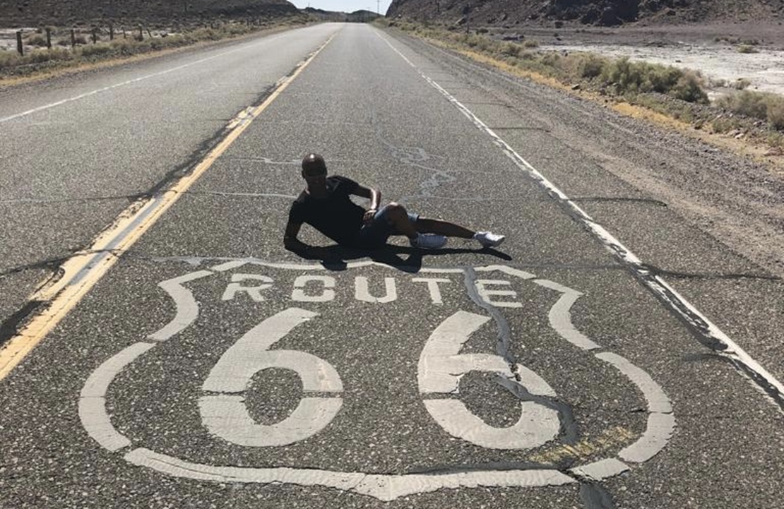 Road-trip aux États-Unis - Jean-Marc devant la marque de la célèbre route 66 - Amplitudes