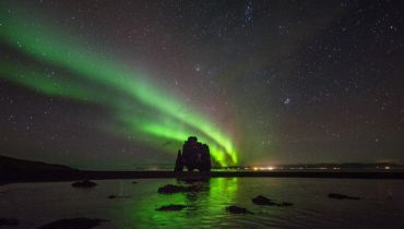 Voyage sur mesure en Islande - La silhouette d'un rocher devant les aurores boréales - Amplitudes