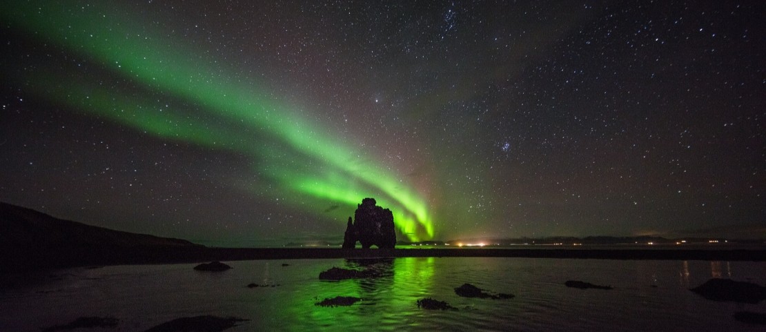 Voyage sur mesure en Islande - La silhouette d'un rocher devant les aurores boréales - Amplitudes