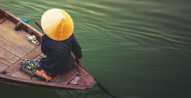 Vietnam - Portrait d'une femme qui rame dans son bateau sur le Mékong