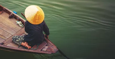 Vietnam - Portrait d'une femme qui rame dans son bateau sur le Mékong