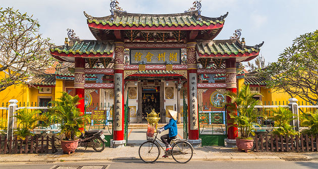 Vietnam - Portrait d'une femme locale en vélo devant la salle de l'assemblée Trieu Chau à Hoi An