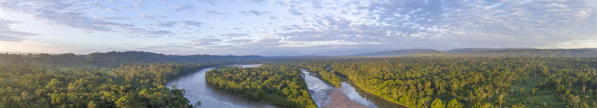 Aerial panorama of the Rio Napo at dawn in the Ecuadorian Amazon with the first rays of the sun illuminating the forest canopy