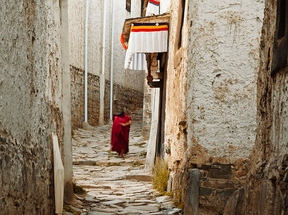 Vieux moine marchant dans une ruelle de Xigaze - Tibet