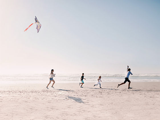 Famille jouant au cerf-volant sur une plage