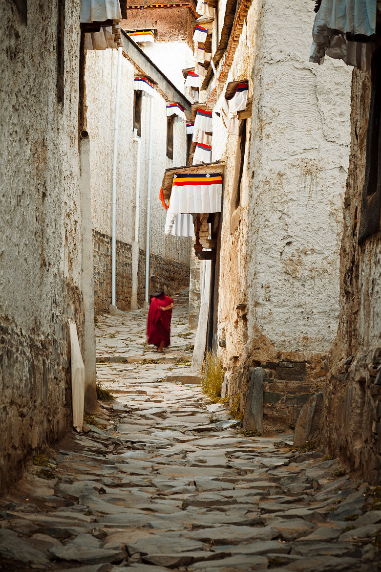 Vieux moine marchant dans une ruelle de Xigaze - Tibet