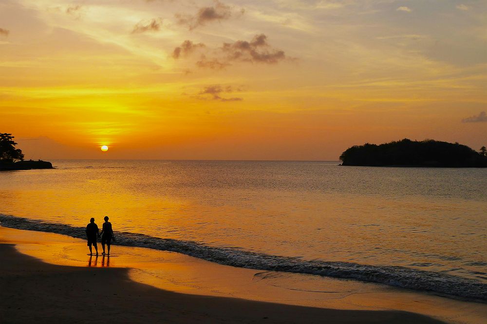Couple marchant devant un couché de soleil sur une plage, Sainte Lucie