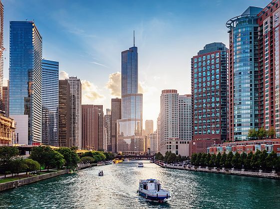 Chicago Cityscape from Chicago River Waterfront at Dusk. Small boats and tourist ferries cruising on the Chicago River towards the Michigan Lake. Chicago, Illinois, USA.