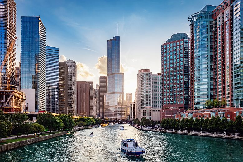 Chicago Cityscape from Chicago River Waterfront at Dusk. Small boats and tourist ferries cruising on the Chicago River towards the Michigan Lake. Chicago, Illinois, USA.