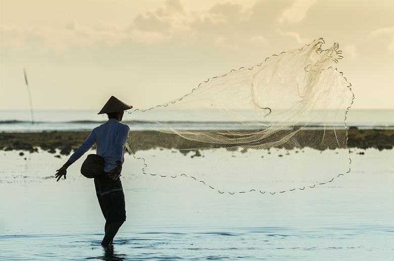 Bali - Portrait d'un pêcheur qui jette son filet dans la mer