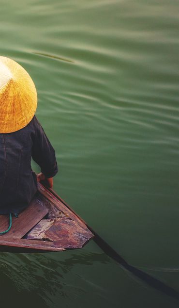 Vietnam - Portrait d'une femme qui rame dans son bateau sur le Mékong