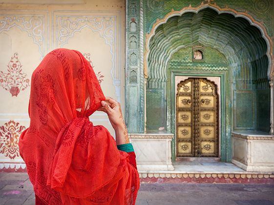 Inde - Portrait d'une femme en habit traditionnel rouge qui regarde le portail du palais de la ville de Jaipur 