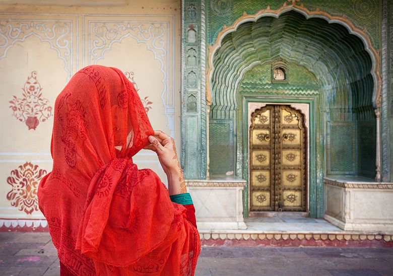Inde - Portrait d'une femme en habit traditionnel rouge qui regarde le portail du palais de la ville de Jaipur 