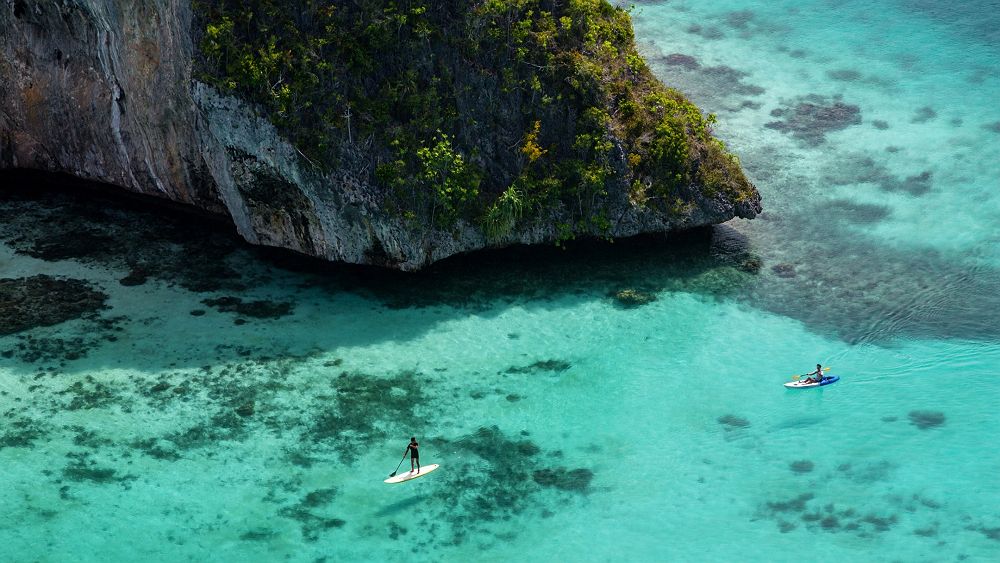 Raja Ampat, vue aérienne, eau turquoise, couple faisant du kayak et du paddle, Indonésie