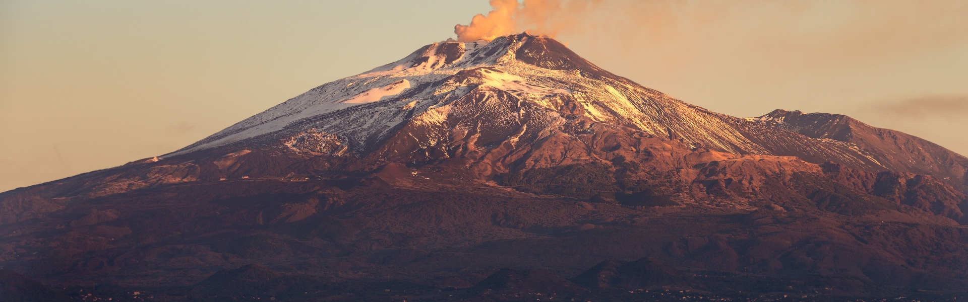 volcan l'etna et son panache de fumée avec en contrebas la ville de catane au coucher du soleil - sicile en italie