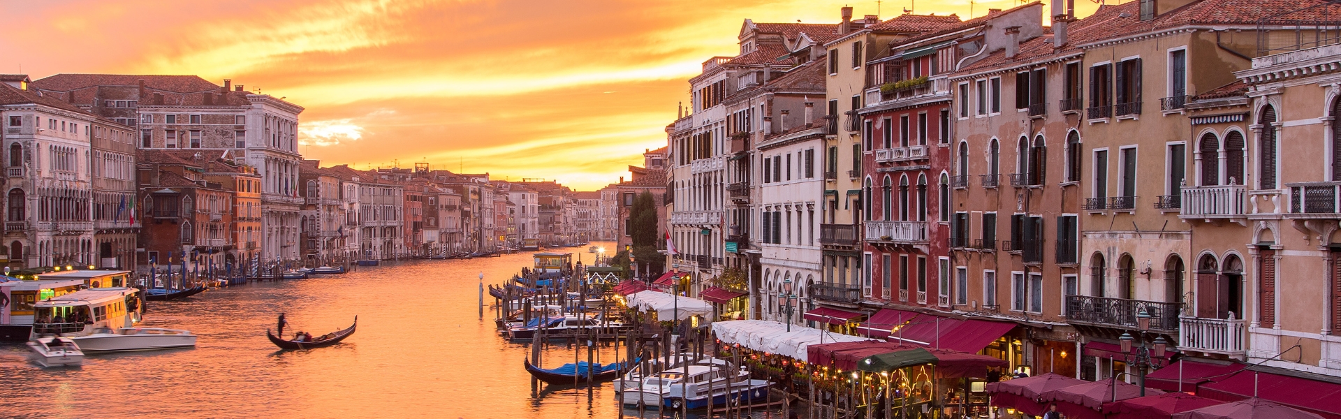 gondolier sur le grand canal de venise border par la ville au soleil couchant