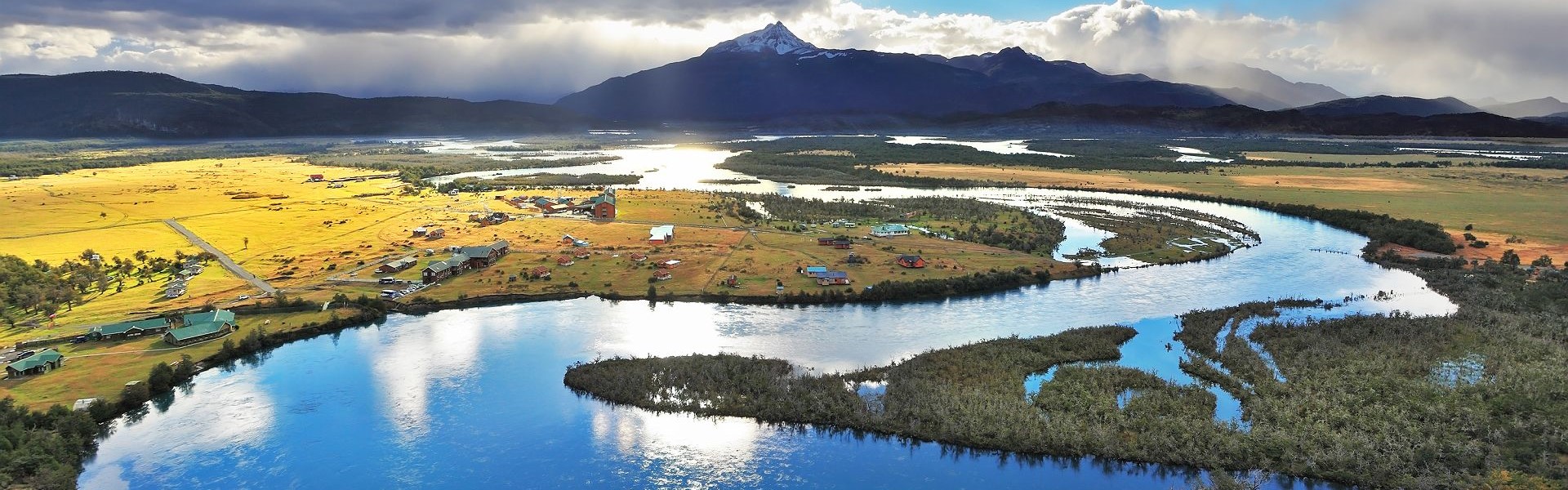 pampa dorée traversée par un cours d'eau et sommets montagneux au parc national torres del paine en patagonie chilienne