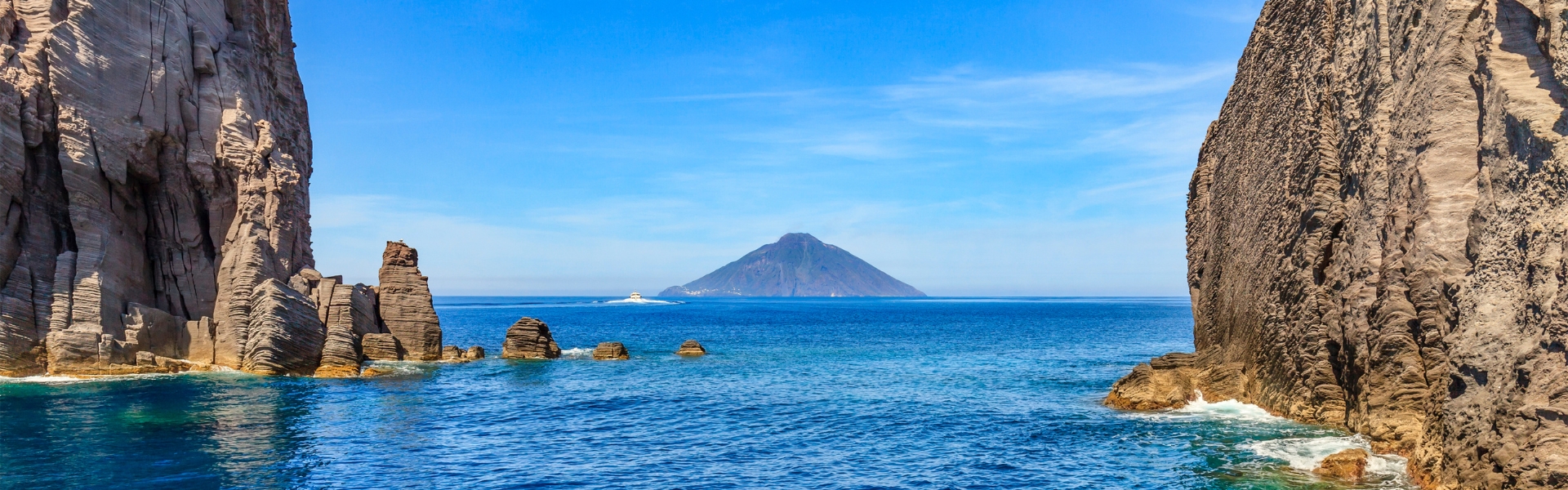 l'île de stromboli se profile parmi les rochers au large de l'île de panarea - îles éoliennes en sicile en italie