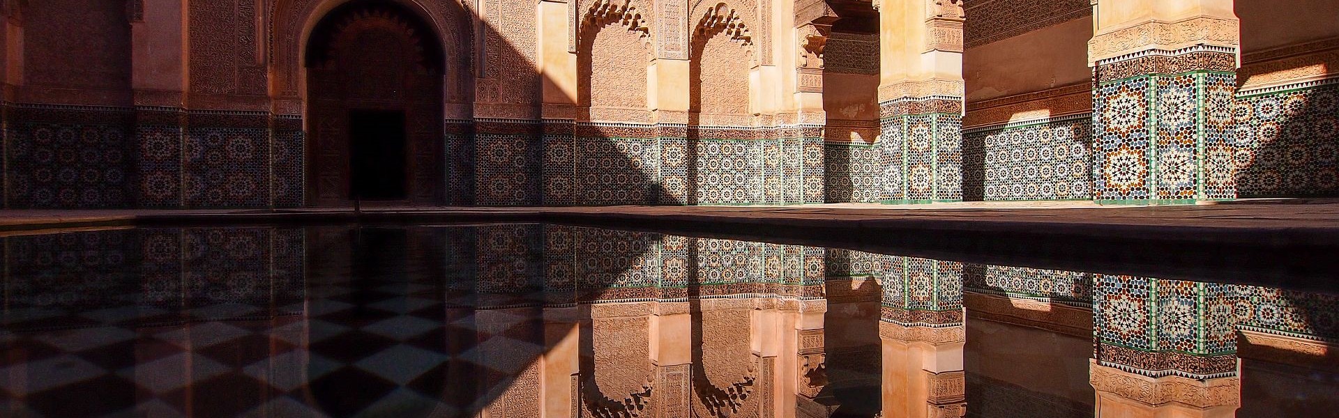 la médersa ben youssef se reflétant dans l'eau d'un bassin à marrakech au maroc