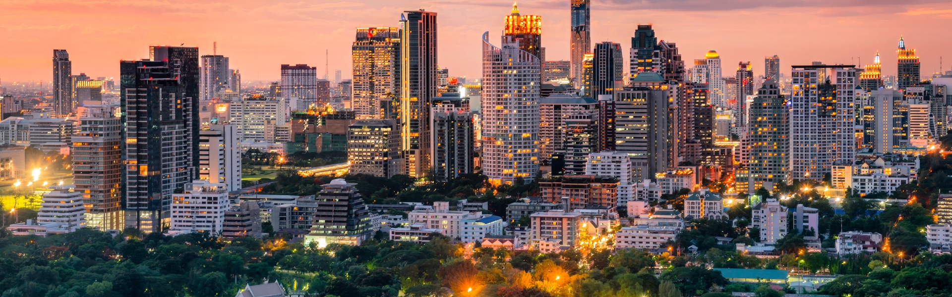 quartier silom à bangkok avec ses gratte-ciel et sa végétation au coucher du soleil