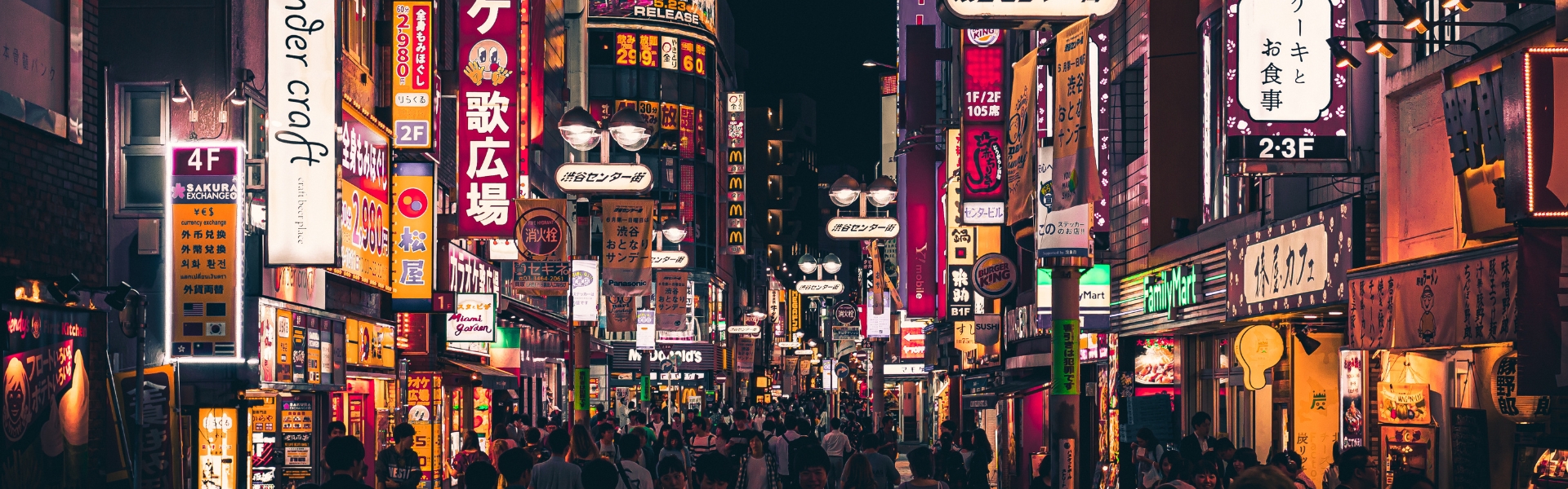 foule marchant dans les rues éclarirées par les néons des enseignes de tokyo le soir