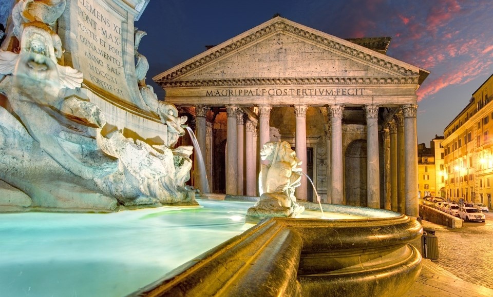 le panthéon derrière la fontaine à rome au crépuscule éclairés par les lumières de la ville
