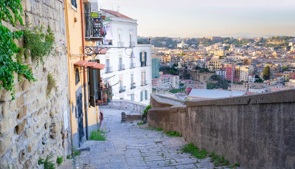 ruelle pavée dans les hauteurs de naples avec une vue dégagée sur la ville en contrebas