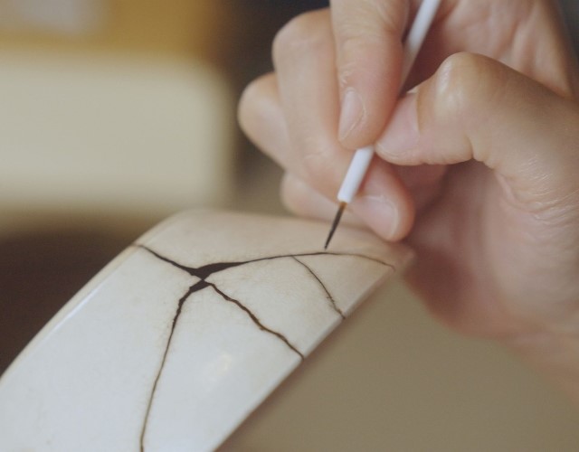 une femme répare une poterie grâce à l'art ancestral du kintsugi