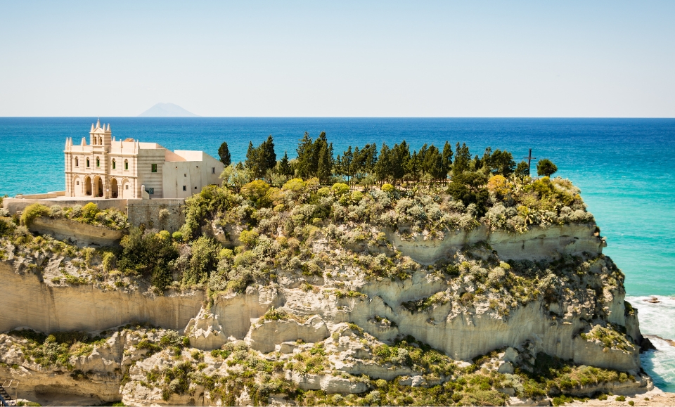 église de santa maria dell'isola érigée sur un rocher à tropea en calabre, mer tyrrhénienne et volcan stromboli au second plan